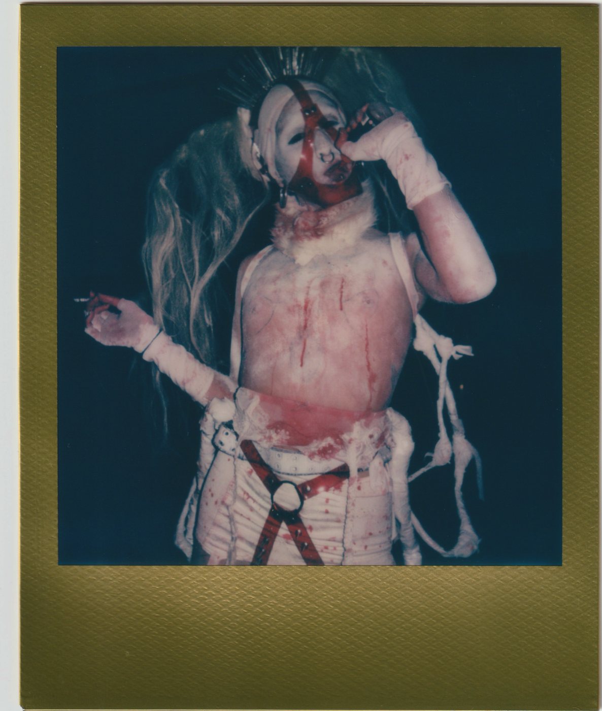 Person in white bandages and a red harness with a spiked crown