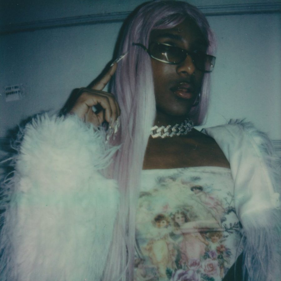 Person with a lilac wig, sunglasses and a white fur jacket