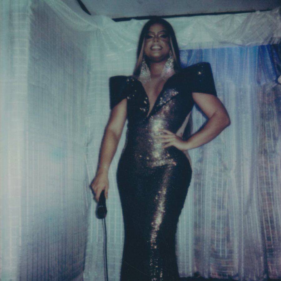 Woman in a sequined gown holding a microphone on a draped stage
